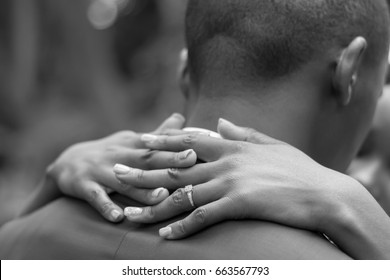 Black African Man And Woman Bridal Wedding Couple Bride Holding Groom Around Neck With Her Fingers Intertwined With Focus On Wedding Ring And Hands Closeup No Faces In Black And White