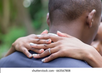 Black African Man And Woman Bridal Wedding Couple Bride Holding Groom Around Neck With Her Fingers Intertwined With Focus On Wedding Ring And Hands Closeup No Faces