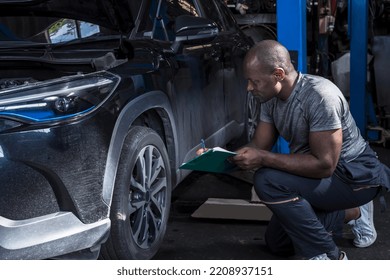 Black African mechanic holding clipboard checking car problem lists in auto repair shop, African American car technician working in garage, black mechanic man ,car repair and maintenance concept - Powered by Shutterstock