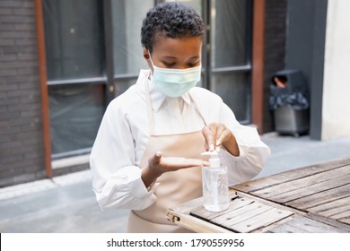 Black African Woman Shop Keeper, Small Business Owner Do A Business Reopening Preparation Work By Wearing Proper Face Mask And Cleaning Her Hand With Alcohol Gel Hand Sanitizer Before Start Working