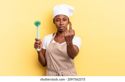 Black Afro Chef Woman Feeling Angry, Annoyed, Rebellious And Aggressive, Flipping The Middle Finger, Fighting Back. Cleaning Dishes Concept