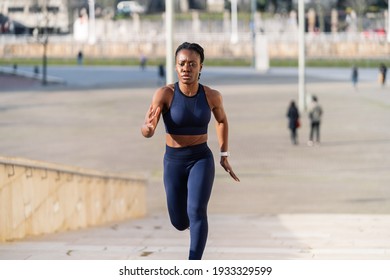 black afro girl dressed as a runner running up a flight of steps in the city at sunset - Powered by Shutterstock