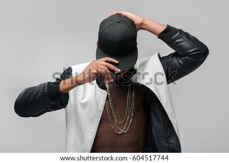 Black afroamerican rebellious rapper on grey background. Closed face, rejection, separated, reluctance to see, breaking off. Ghetto, challenge to society, cheeky, cool