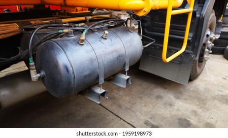 Black air tank for truck brake system. Brass fittings with air breeze on the dirty twin cylinders on the racks of large trucks. On a cement patio background with a copy space. Selective focus