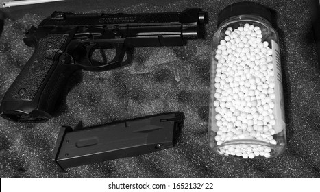 Black Airsoft Handgun Pistol With Magazine & White 6mm White Pellets On Textured Background