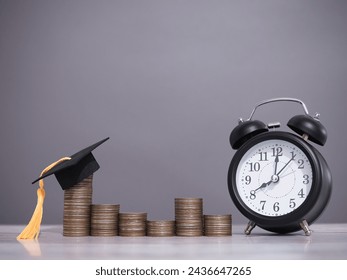 Black alarm clock, Graduation hat and stack of coins. The concept of saving money, manage time to success for education, student loan, scholarship, tuition fees in the future - Powered by Shutterstock