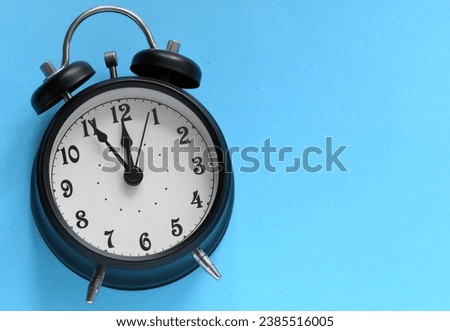 Black alarm clock on a blue background.