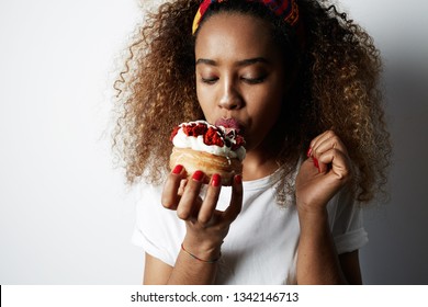 Black American African Woman Making A Mess Eating A Huge Fancy Dessert Over White Background.