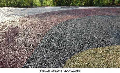 Black Asphalt. Pebble Stone Flooring With Epoxy Resin In City Park. Pebble Stone Is Yellow And Red.