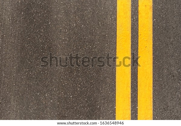Black asphalt road texture with marking\
background. Double yellow line on asphalt\
road.