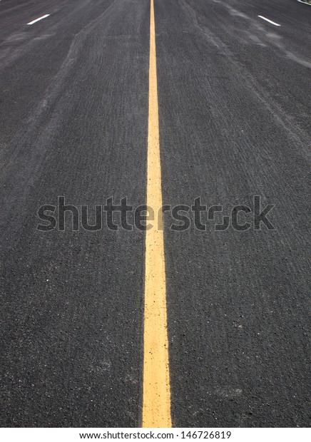 Black asphalt\
road, yellow lines separate\
lanes.