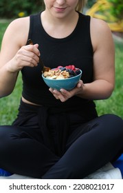 Black Athlete Woman On Grass Eats Granola Peanuts Blackberries Blueberries Bananas Strawberries Oats In Bowl In Her Palm