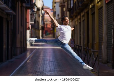 Black athletic man doing an acrobatic jump outdoors