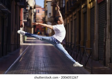 Black athletic man doing an acrobatic jump outdoors