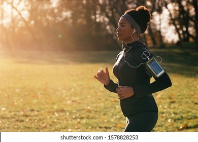 Black Athletic Woman Running While Exercising In The Park. Copy Space. 