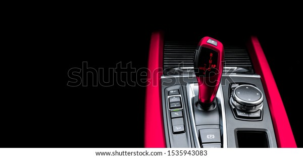 Black Automatic gear stick\
of a modern car. Modern car interior details. Close up view. Car\
detailing. Automatic transmission lever shift isolated on black\
background.