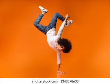 Black awesome man balancing on one hand on orange background - Powered by Shutterstock