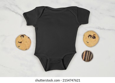 Black Baby Onesie Surrounded By Tempting Chocolate Chip And Chocolate Frosted Cookies.