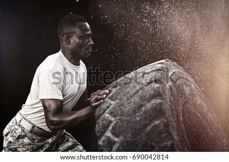 Black background against military soldiers exercising with tyre