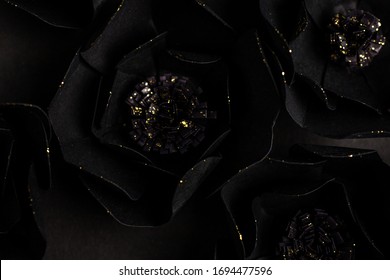 black background with a big flowers with gold shiny glittering, made of paper, top view, macro