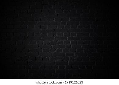 Black background. Brick wall texture with vignette. Monochrome photo.