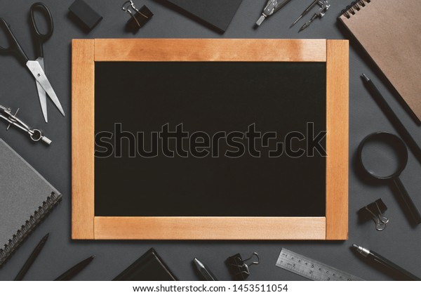 Black background with chalkboard and school or\
college supplies, copy space\
