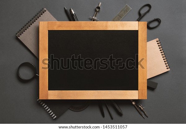 Black background with chalkboard and school or\
college supplies, copy\
space