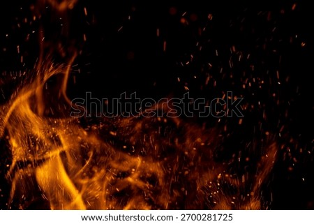 A black background with a fire in the foreground. The fire is surrounded by a lot of sparks
