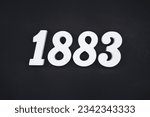 Black for the background. The number 1883 is made of white painted wood.