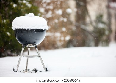 Black barbeque grill covered with snow outdoors on winter day