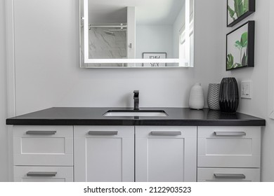 black bathroom countertop, with a mirror above
