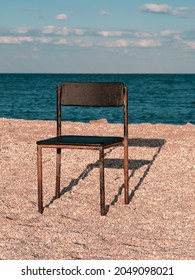 Black Beach Chair On Empty Sand Beach With Blue Sea Water Background. Minimalism Style Autumn Travel Relaxation, Spring Fall Vacation. No People, Nobody, Introversion Psychology Melancholia Depression