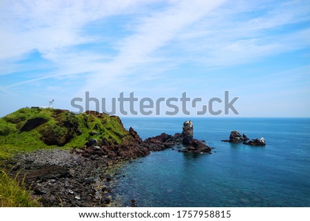 Black beach or cliff from Volcanic rocks with blue sky and ocean at seopjikoji cape, Jeju island, South korea.