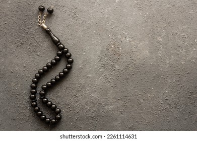 Black beads Muslim prayer rosary on dark stone background, symbol of islam religion