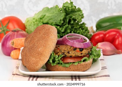 A Black Bean Vegetarian Burger On A Whole Wheat Roll With Tomato, Onion And Greens.