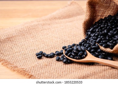 Black Beans In  A Spoon Wood From Bag Spilled On A Wooden Table, Close-up And Macro Shot, Organic Food From Nature Concept.







