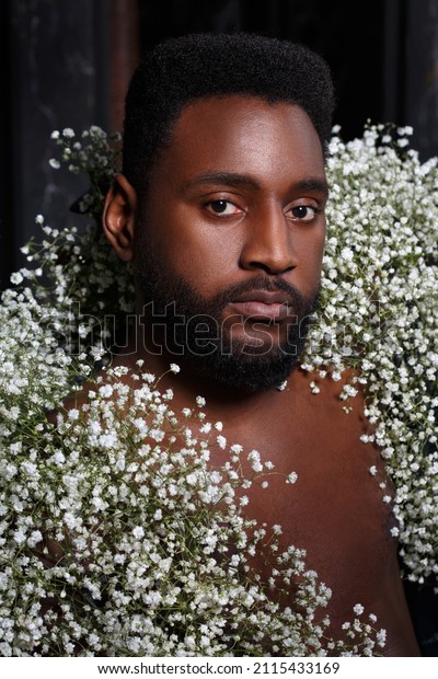 A black bearded attractive man dressed in white\
gypsaphylla flowers.
