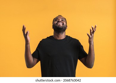 Black Bearded Man Looking Upward While Posing With Hands Up Isolated Over Yellow Background