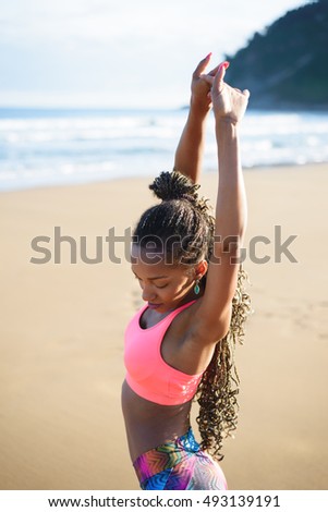 Black beautiful sportswoman stretching and training at the beach on summer. Fitness outdoor workout.