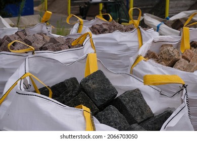 Black, And Beige Cobblestones In A Polypropylene Big Bag With Yellow Tape Slings. Packaging Of Natural Stone In Soft Containers.