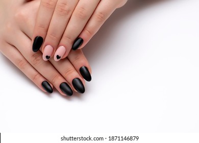 Black, beige matte manicure on long oval nails with painted black hearts on a white background close-up
