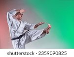 Black belt trainer performing formal exercises against a colored background with red and green tints