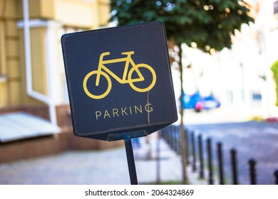 A black bicycle sign with a picture of yellow bike and text parking. Convenient infrastructure of big city streets. Parking area space for two-wheelers transport on the European street. Urban concept