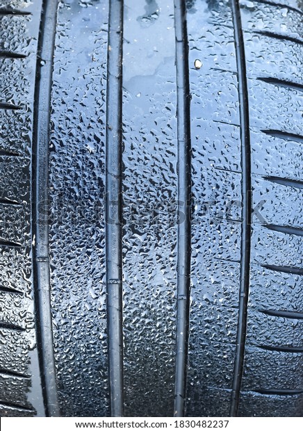 Black big tires in a close up view\
with water drops. Tire tread problems. Solutions\
concept.