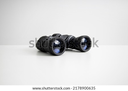 Black binoculars lying on a white background. Side view.