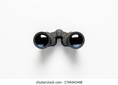 Black binoculars on a white background. Flat lay, top view