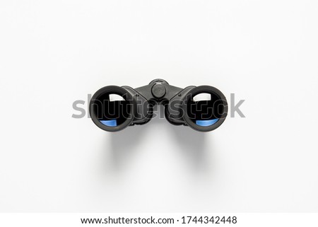 Black binoculars on a white background. Flat lay, top view