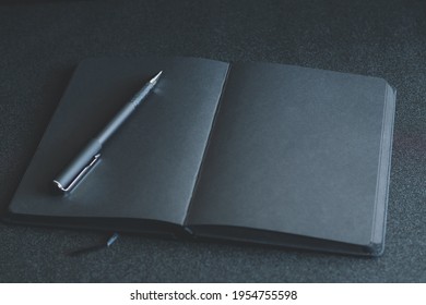 Black blank notebook or plain notepad or diary or journal for writing text and message with pen on table or desk as background with copy space. Still lifestyle photo concept.