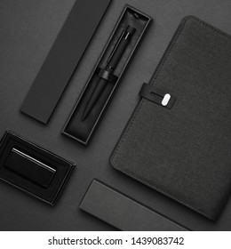 Black Blank Unbranded Stationary Notebook With Pen And Luxury Pen Case With Lighter On Black Background From Aerial View