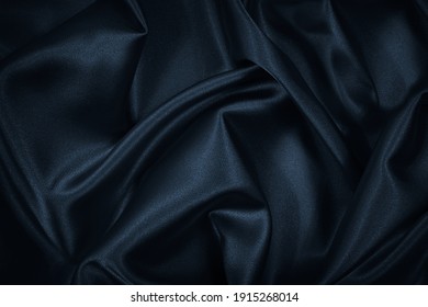 Schwarz-blauer abstrakter Hintergrund. Dunkelblaue Seidenmatte. Schöne weiche Falten auf der Oberfläche des Gewebes. Navy blauer, eleganter Hintergrund mit Kopienraum für Ihr Design. Webbanner.          – Stockfoto